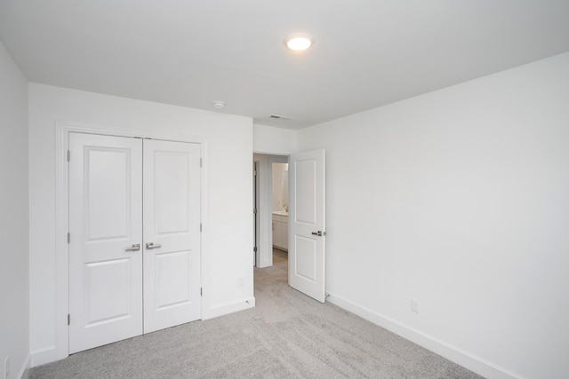 unfurnished bedroom with light carpet, baseboards, and a closet