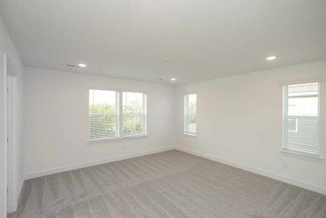spare room featuring light colored carpet, baseboards, and recessed lighting