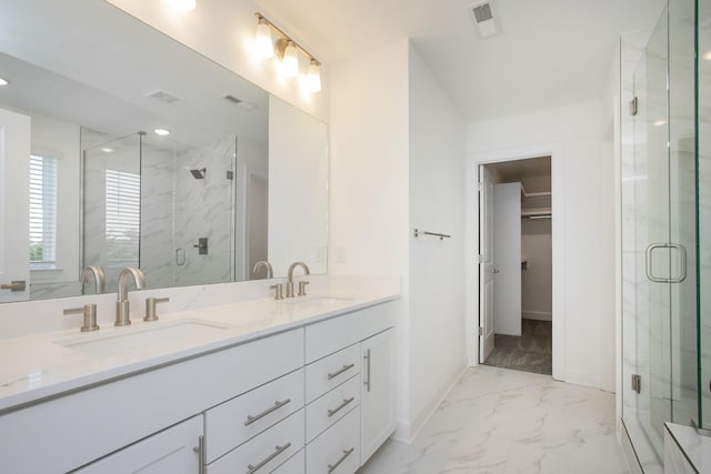 full bath with a marble finish shower, marble finish floor, a walk in closet, and a sink