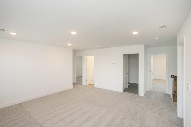 empty room featuring baseboards, light carpet, visible vents, and recessed lighting