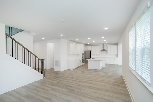 unfurnished living room featuring light wood-type flooring, a healthy amount of sunlight, and a sink
