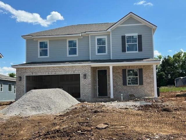 view of front of property featuring covered porch, a garage, brick siding, and driveway
