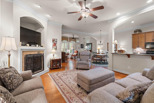 1230 Chickadee Cir, Hermitage, TN 37076 - living area featuring crown molding, light wood-type flooring, ceiling fan, arched walkways, and a fireplace with raised hearth