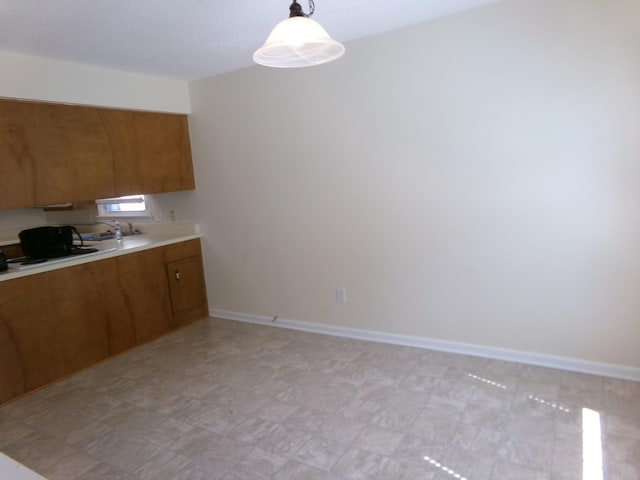224 Gaines Cir, Estill Springs, TN 37330 - kitchen featuring brown cabinetry, light countertops, hanging light fixtures, baseboards, and light floors