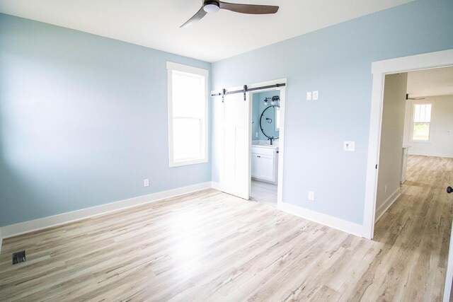 105 Shephard St N, Winchester, TN 37398 - unfurnished bedroom with light wood finished floors, ensuite bathroom, visible vents, a barn door, and baseboards