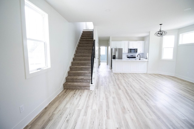 105 Shephard St N, Winchester, TN 37398 - unfurnished living room with a sink, stairs, light wood-type flooring, an inviting chandelier, and baseboards