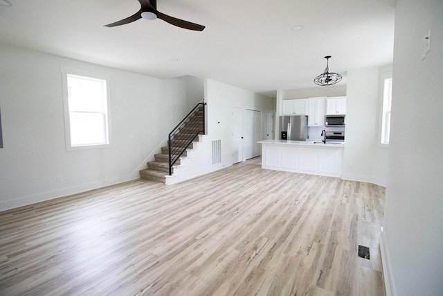 105 Shephard St N, Winchester, TN 37398 - unfurnished living room with ceiling fan with notable chandelier, light wood-type flooring, visible vents, stairway, and baseboards