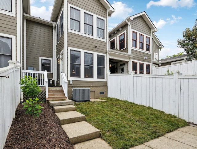 rear view of house featuring central AC unit, fence, and crawl space