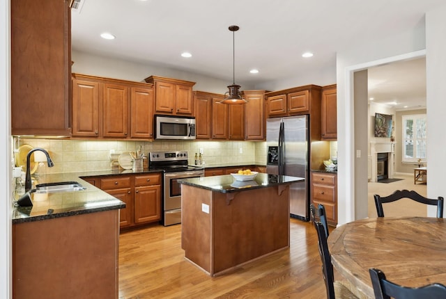 kitchen with light wood-style floors, stainless steel appliances, decorative backsplash, and a sink