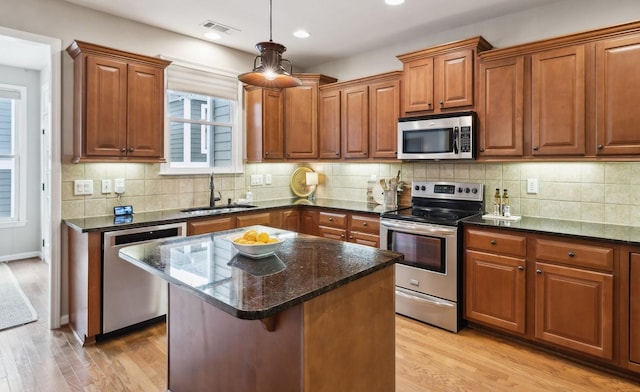 kitchen with a sink, light wood finished floors, stainless steel appliances, and brown cabinets