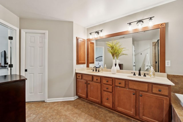 full bathroom featuring a bath, tile patterned floors, double vanity, and a sink