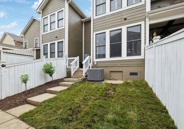 back of property featuring fence, cooling unit, and a lawn