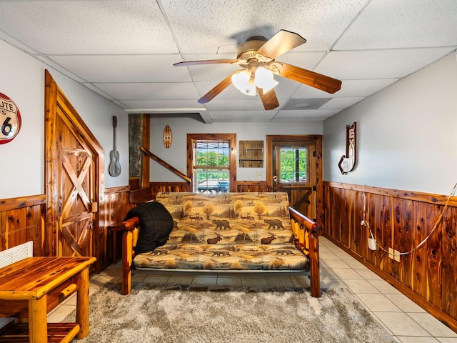 375 Good Hope Rd, Leoma, TN 38468 - bedroom featuring a wainscoted wall, wood walls, a drop ceiling, tile patterned floors, and a ceiling fan