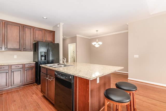 kitchen with black appliances, light wood-type flooring, a sink, and a kitchen bar