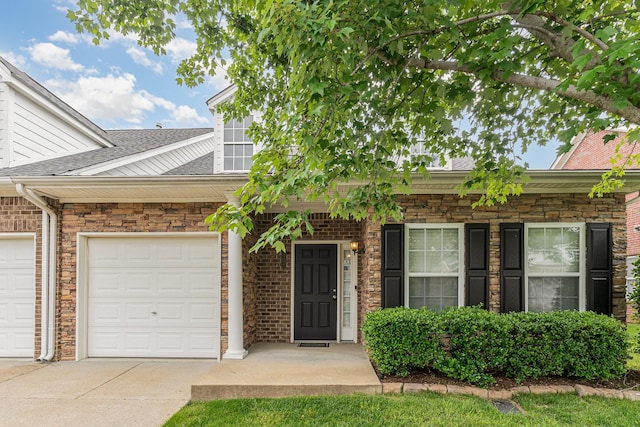 view of front of home featuring an attached garage, concrete driveway, and a shingled roof