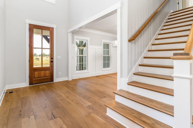 foyer entrance with stairway, ornamental molding, baseboards, and hardwood / wood-style floors