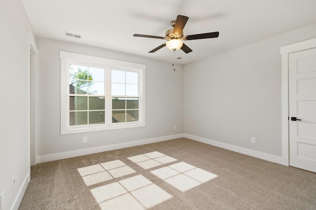 spare room with carpet flooring, visible vents, baseboards, and ceiling fan