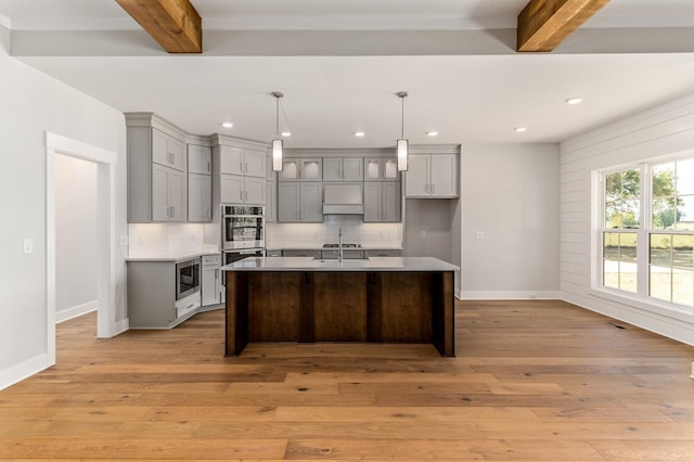 kitchen with gray cabinetry, beam ceiling, baseboards, and tasteful backsplash