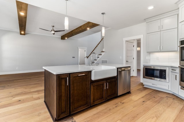 kitchen featuring a sink, beam ceiling, dishwasher, black microwave, and light countertops