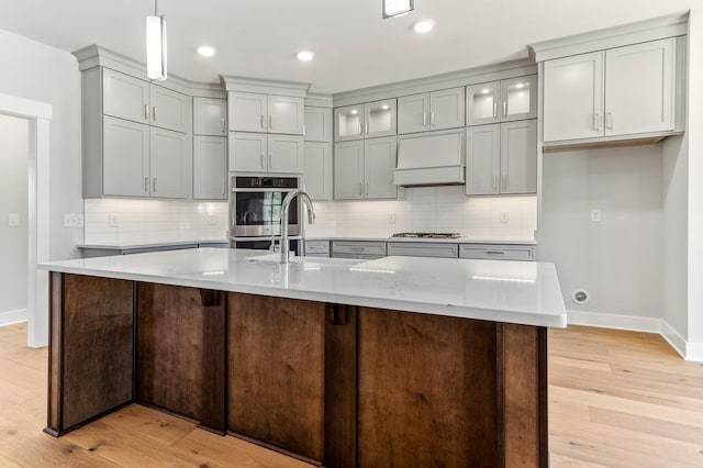 kitchen featuring baseboards, light wood-style floors, gray cabinetry, and a sink