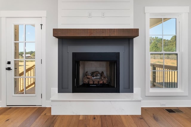 interior details with visible vents, a fireplace with raised hearth, and wood finished floors