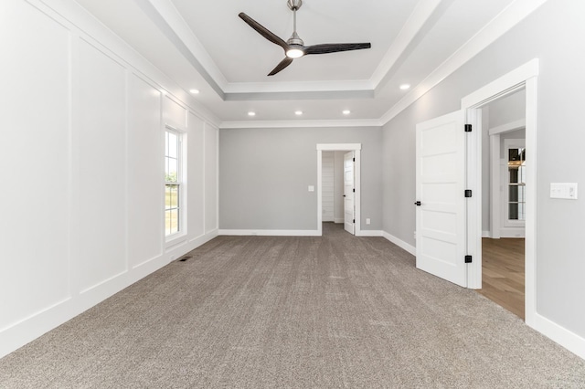 empty room with a tray ceiling, ceiling fan, carpet floors, and recessed lighting