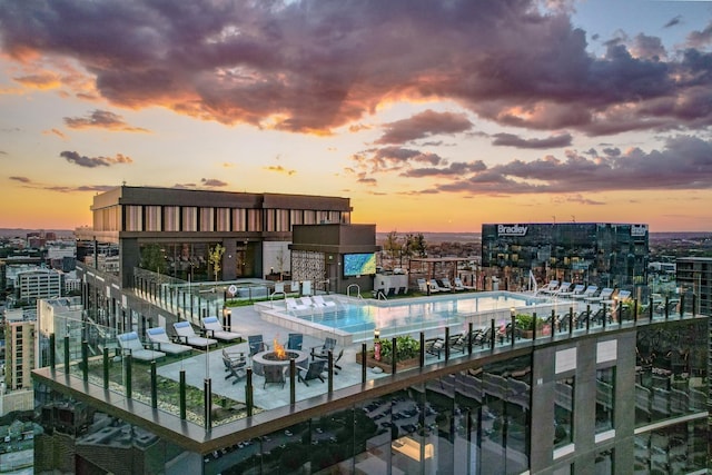 view of swimming pool with an outdoor fire pit and a city view