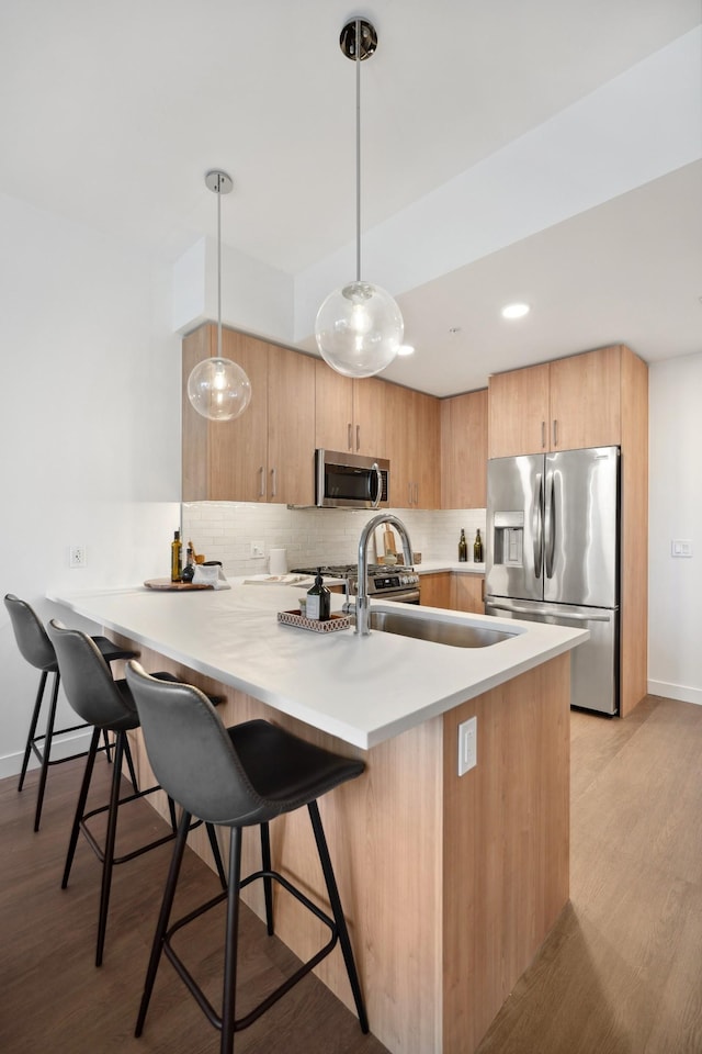 kitchen with stainless steel appliances, a kitchen breakfast bar, light wood-style flooring, backsplash, and baseboards
