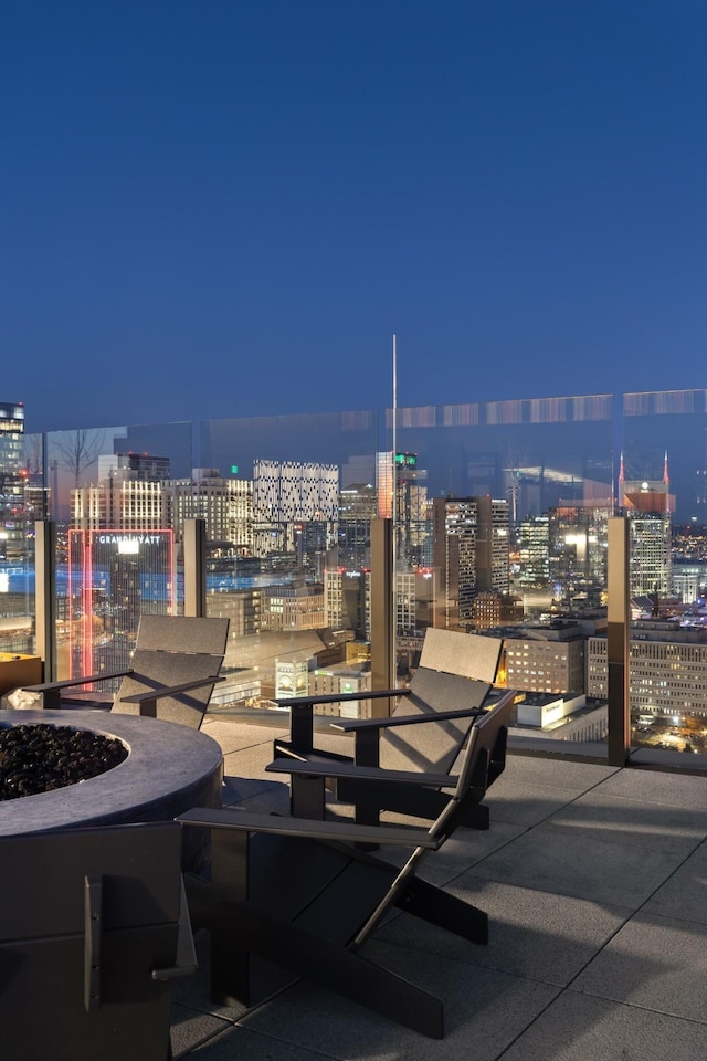 patio at night with an outdoor fire pit and a view of city lights