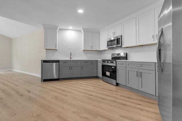 4048 Lancashire Dr, Antioch, TN 37013 - kitchen featuring appliances with stainless steel finishes, gray cabinets, light wood finished floors, backsplash, and recessed lighting