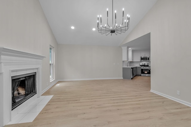 4048 Lancashire Dr, Antioch, TN 37013 - unfurnished living room featuring high vaulted ceiling, a sink, light wood finished floors, a chandelier, and baseboards