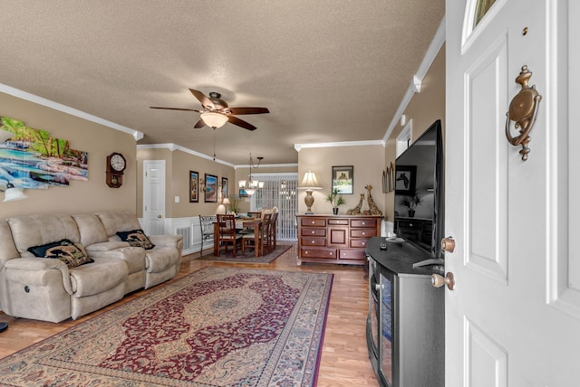 living area featuring a ceiling fan, a textured ceiling, light wood finished floors, crown molding, and a chandelier