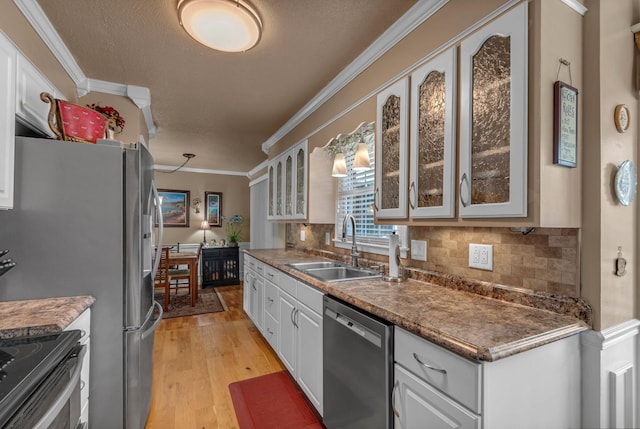 kitchen featuring dishwasher, light wood finished floors, crown molding, a sink, and decorative backsplash