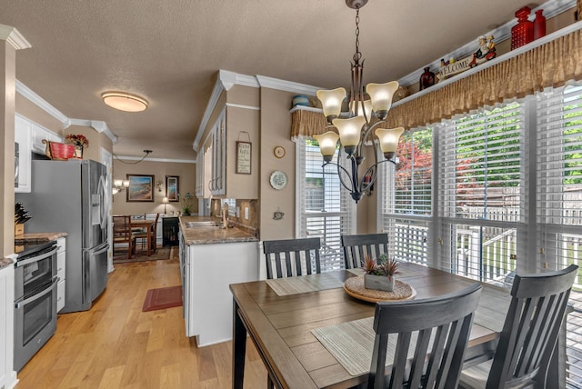 dining area featuring a chandelier, crown molding, light wood finished floors, and a textured ceiling
