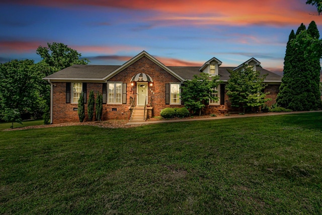 view of front of house with brick siding, a yard, and roof with shingles