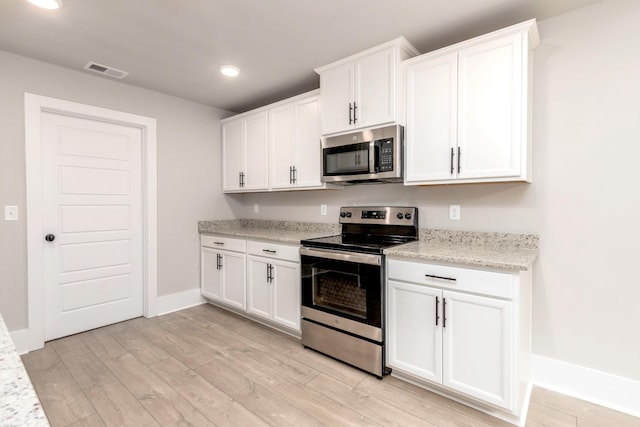 kitchen featuring appliances with stainless steel finishes, visible vents, light wood-style flooring, and white cabinetry