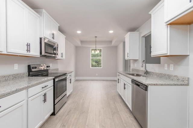 kitchen with recessed lighting, light wood finished floors, a sink, stainless steel appliances, and white cabinets