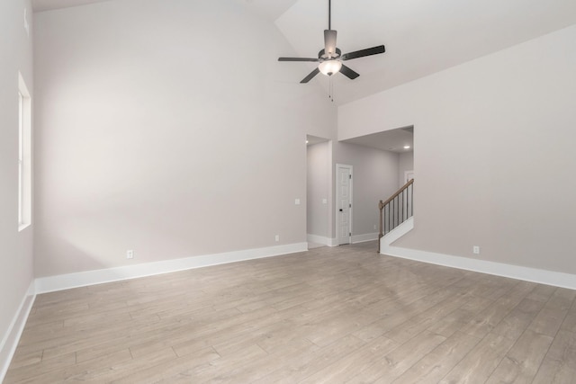 spare room featuring stairs, high vaulted ceiling, a ceiling fan, baseboards, and light wood-style floors