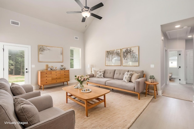 living room with a ceiling fan, visible vents, attic access, and plenty of natural light