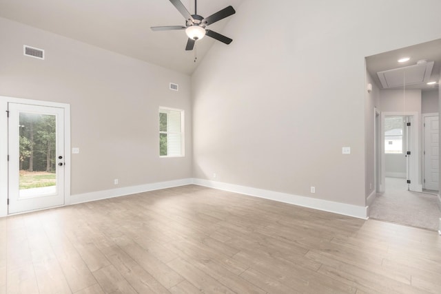 empty room with attic access, a wealth of natural light, ceiling fan, visible vents, and high vaulted ceiling