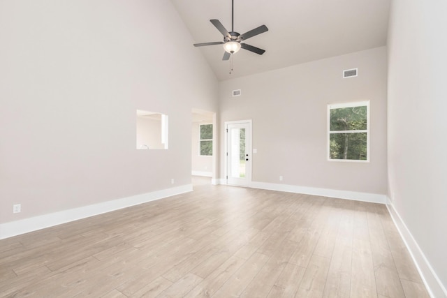 unfurnished room with light wood finished floors, visible vents, ceiling fan, and high vaulted ceiling