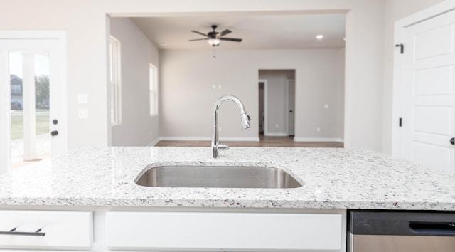 kitchen with a sink, wood finished floors, dishwasher, open floor plan, and light stone countertops