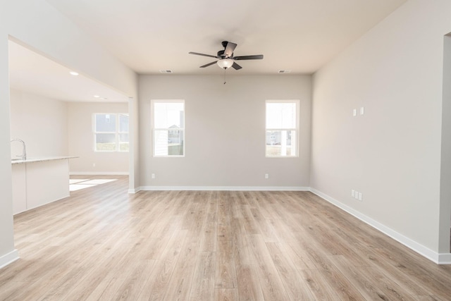 spare room featuring light wood-type flooring, baseboards, and a ceiling fan