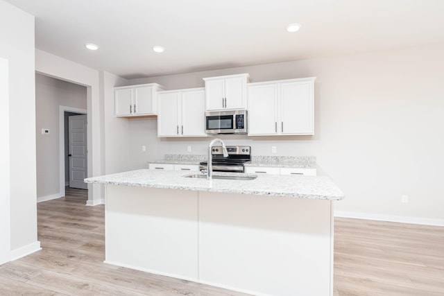 kitchen with white cabinets, appliances with stainless steel finishes, baseboards, and a sink