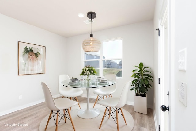 dining space featuring light wood-style floors, visible vents, and baseboards