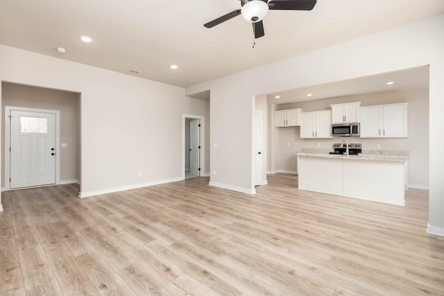 unfurnished living room with ceiling fan, baseboards, light wood finished floors, and recessed lighting