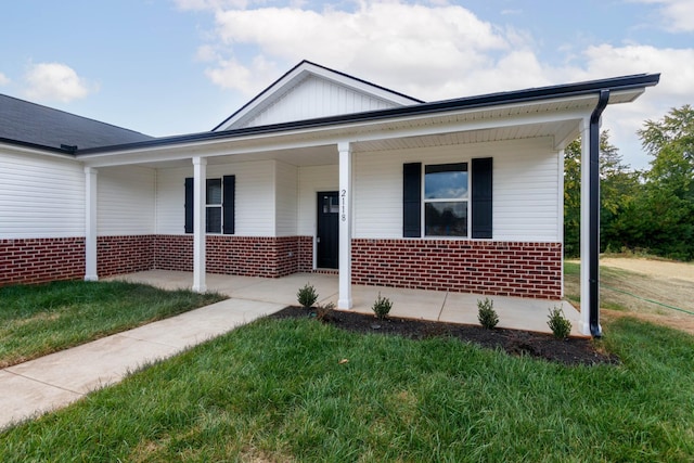 view of front of property with a front lawn, board and batten siding, brick siding, and covered porch