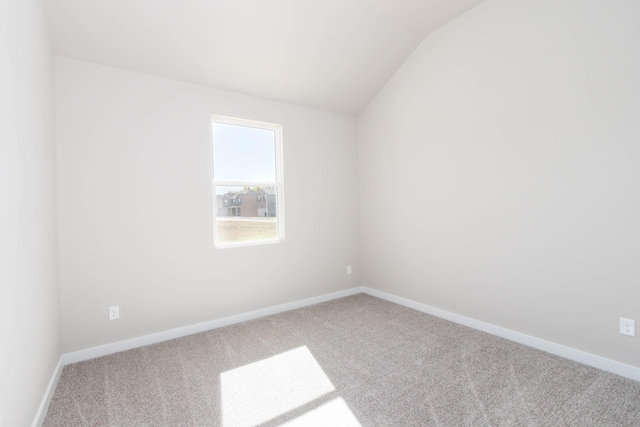 empty room with vaulted ceiling, carpet flooring, and baseboards