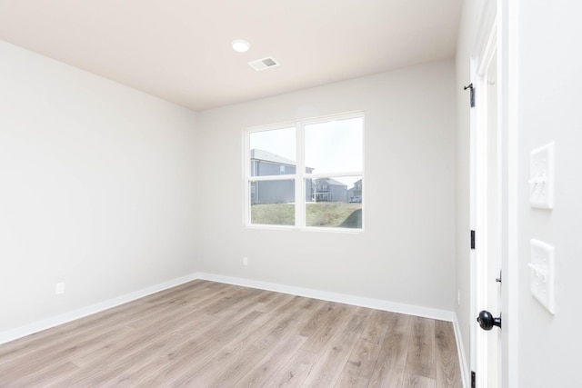 empty room with light wood finished floors, baseboards, and visible vents