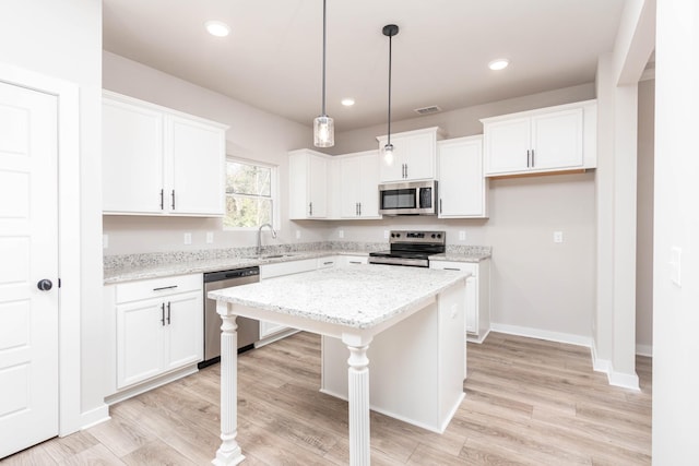 kitchen with white cabinets, appliances with stainless steel finishes, a center island, and a sink